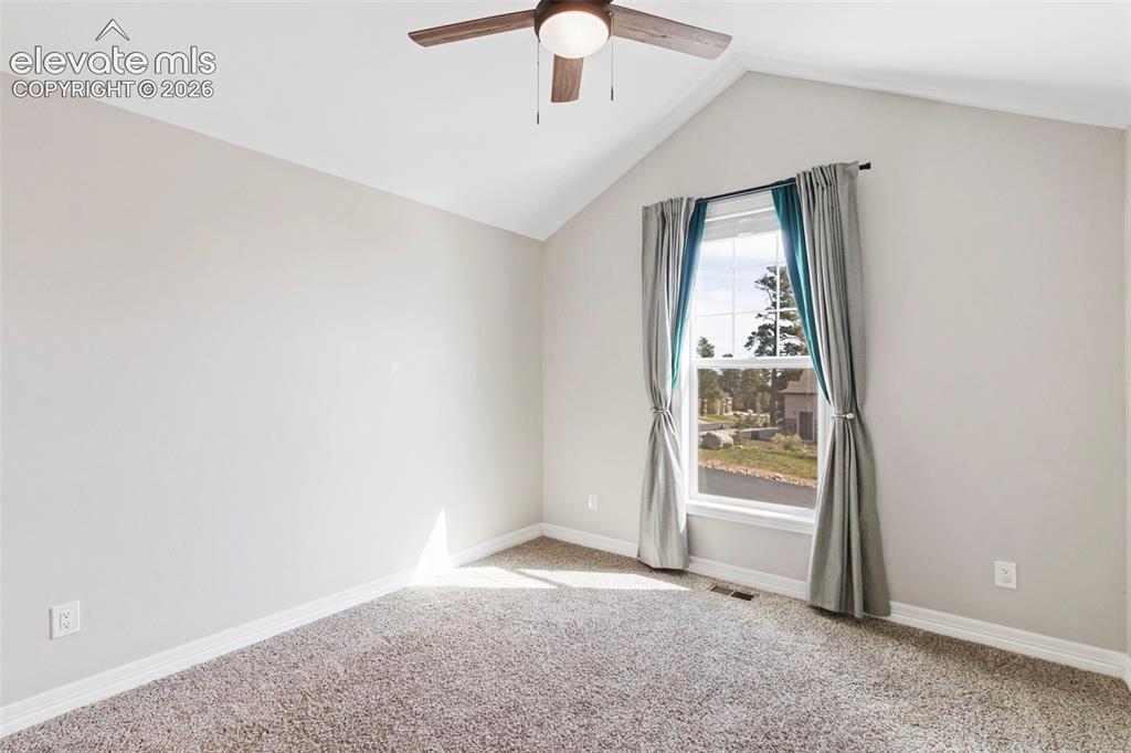 Image 21 of 47: Room featuring a vaulted ceiling with a ceiling fan, a window with exterior