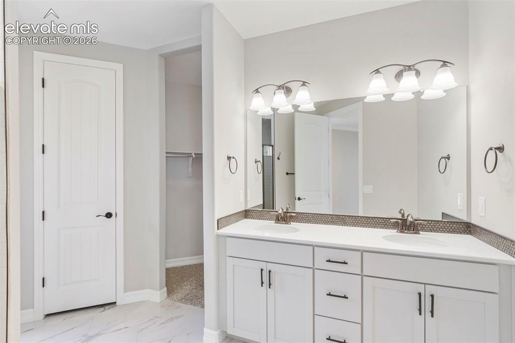 Image 26 of 47: Dual vanity featuring white cabinetry, integrated sinks, white countertops,
