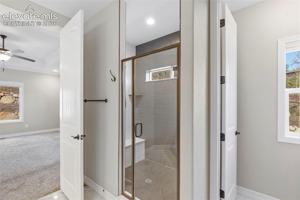 Image 27 of 47: Walk-in shower with a glass enclosure, built-in bench, and tiled walls