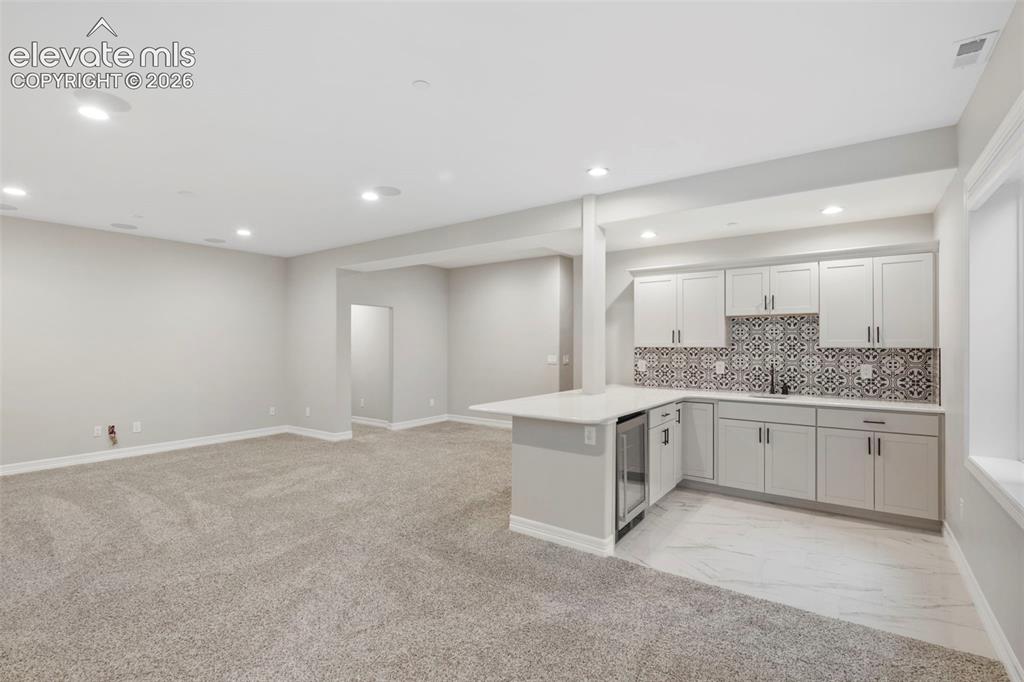 Image 29 of 47: Integrated wet bar with white shaker cabinetry, patterned tile backsplash, 