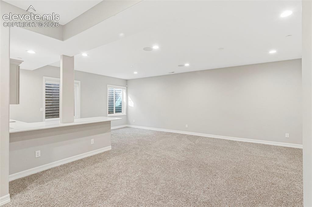 Image 30 of 47: Spacious room featuring neutral carpet flooring, recessed lighting, and a b