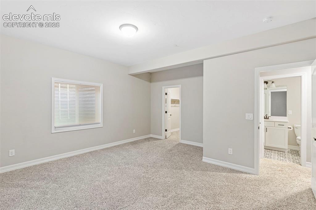 Image 36 of 47: Carpeted room with light neutral walls, a single window with blinds, and a 