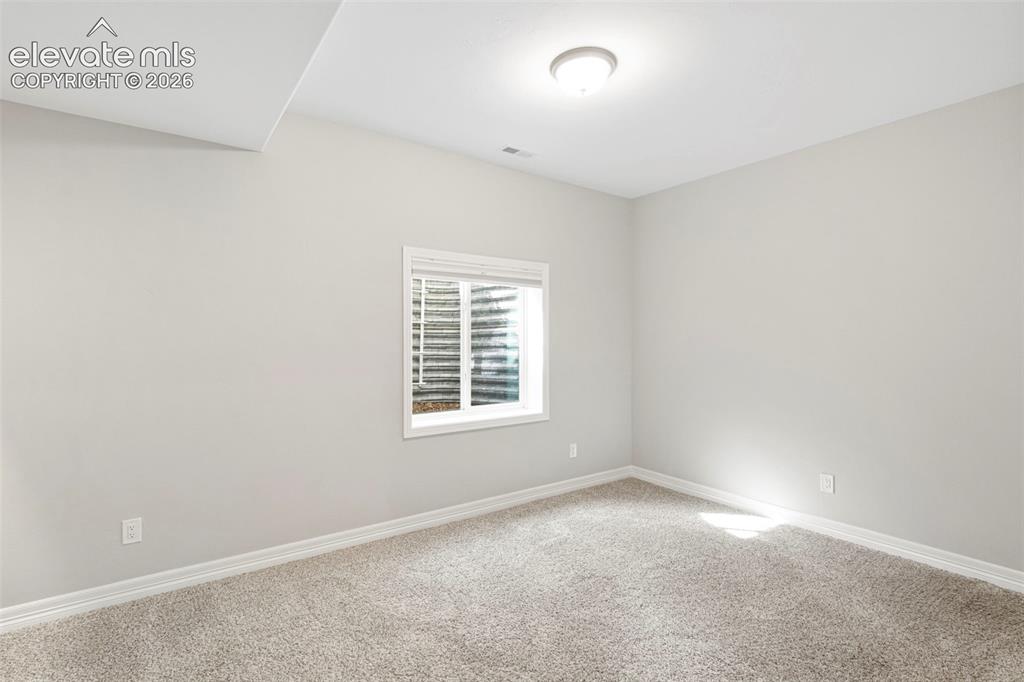 Image 37 of 47: Carpeted room featuring a white-framed window with blinds, light gray walls