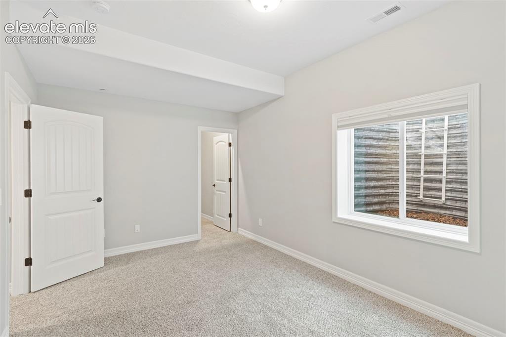 Image 38 of 47: Carpeted room featuring light gray walls, white trim, and a window with whi