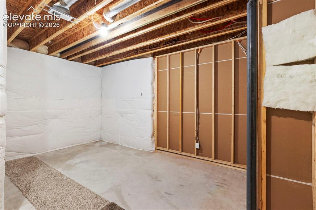 Image 39 of 47: Unfinished basement space featuring exposed wooden ceiling joists, concrete