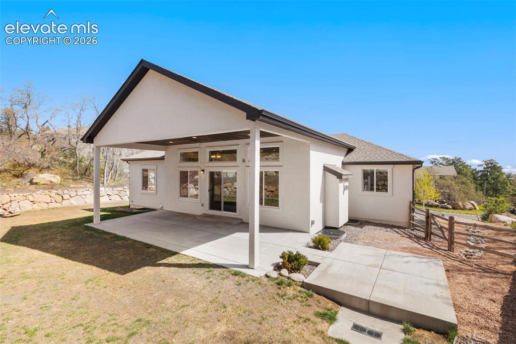 Image 43 of 47: Rear exterior featuring a covered patio, stucco siding, and a gabled roofli