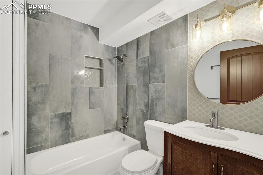 Image 12 of 32: Bathroom featuring tile walls, washtub / shower combination, and vanity