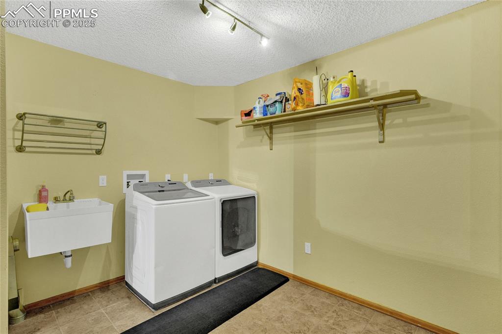 Image 13 of 32: Laundry area with independent washer and dryer, a textured ceiling, and rai