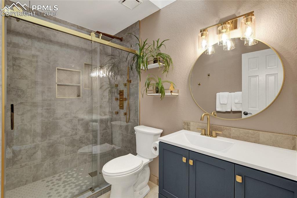 Image 20 of 32: Full bathroom featuring vanity, a stall shower, and a textured wall