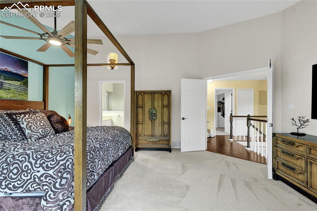 Image 22 of 32: Carpeted bedroom with high vaulted ceiling and connected bathroom