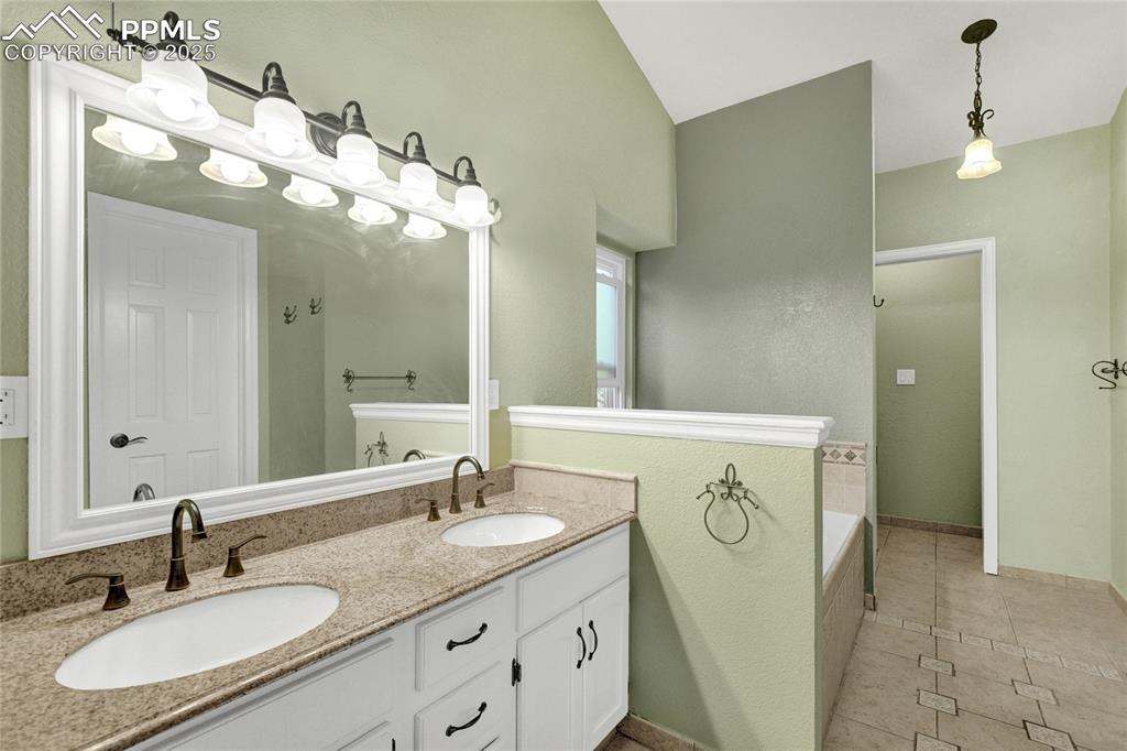 Image 23 of 32: Bathroom with double vanity, tile patterned floors, a garden tub, and lofte
