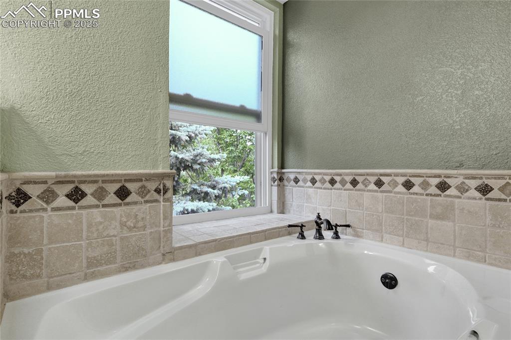 Image 24 of 32: Full bathroom featuring a textured wall and a bath
