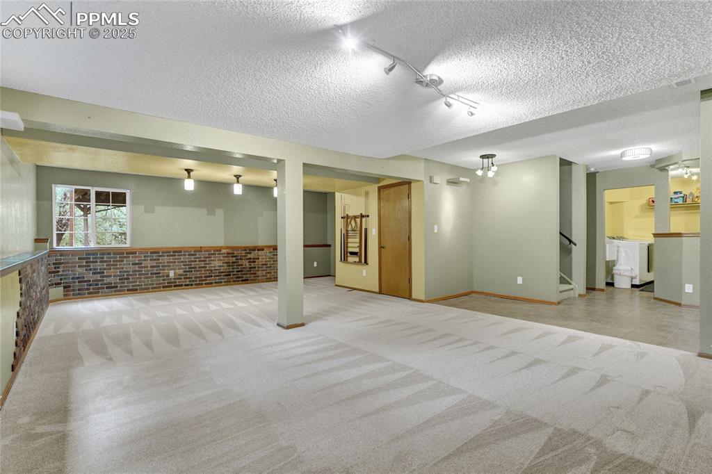 Image 28 of 32: Basement with carpet, a textured ceiling, washer / clothes dryer, stairs, a