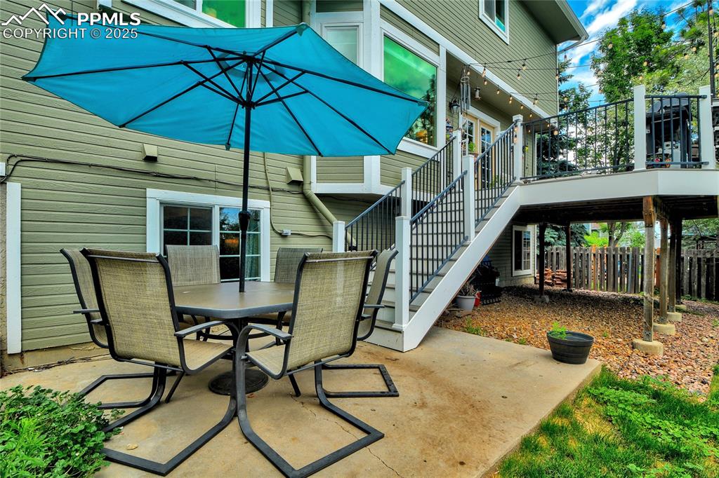 Image 31 of 32: View of patio featuring outdoor dining area, stairs, and a wooden deck