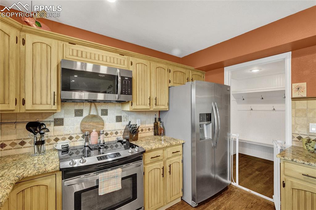 Image 8 of 32: Kitchen with stainless steel appliances, dark wood-style floors, decorative
