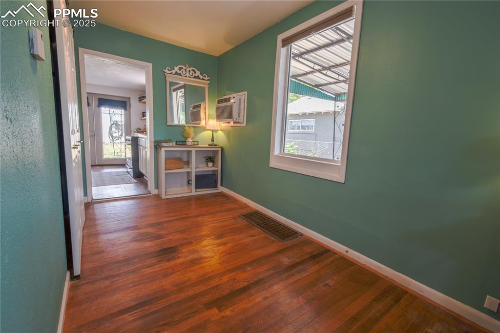 Image 11 of 30: Empty room featuring hardwood / wood-style floors, baseboards, and a wall m