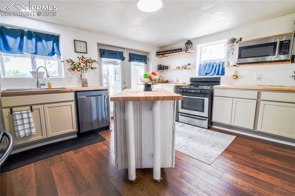 Image 13 of 30: Kitchen featuring wooden counters, stainless steel appliances, a sink, a te