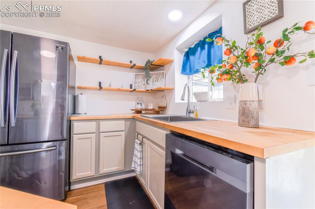 Image 14 of 30: Kitchen featuring stainless steel appliances, a sink, butcher block counter