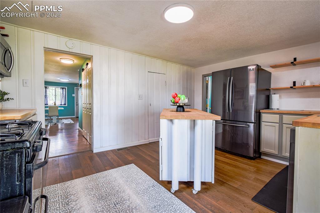 Image 15 of 30: Kitchen with wood counters, appliances with stainless steel finishes, dark 