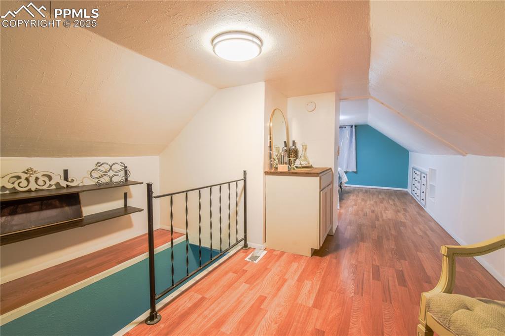 Image 19 of 30: Bonus room featuring a textured ceiling, light wood-style flooring, and vau