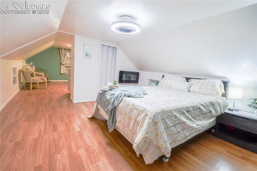 Image 21 of 30: Bedroom featuring wood finished floors, vaulted ceiling, and baseboards