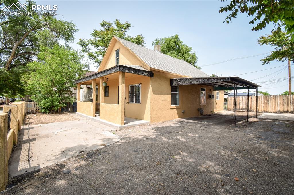 Image 25 of 30: Back of property featuring stucco siding, a carport, and roof with shingles