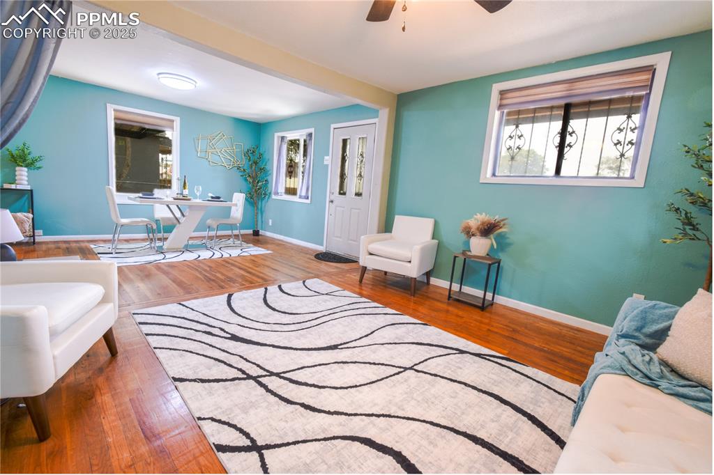 Image 5 of 30: Living area with wood finished floors, ceiling fan, healthy amount of natur