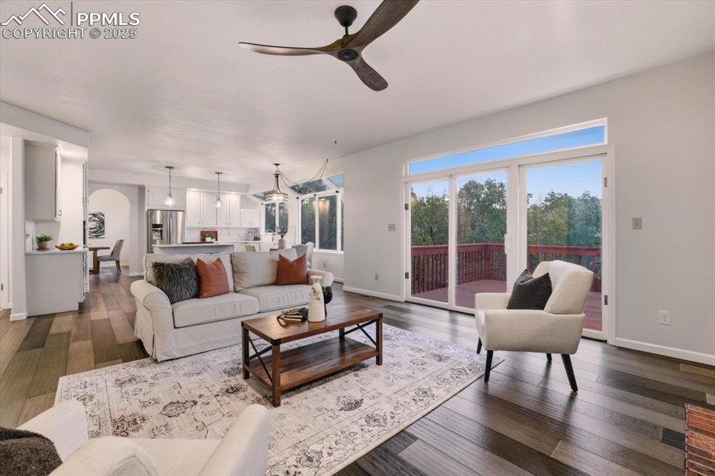 Image 11 of 31: Living area featuring ceiling fan, dark wood-type flooring, and arched walk