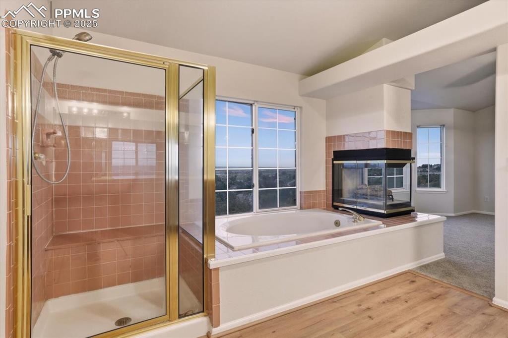 Image 19 of 31: Full bath featuring wood finished floors, a shower stall, a bath, and a til