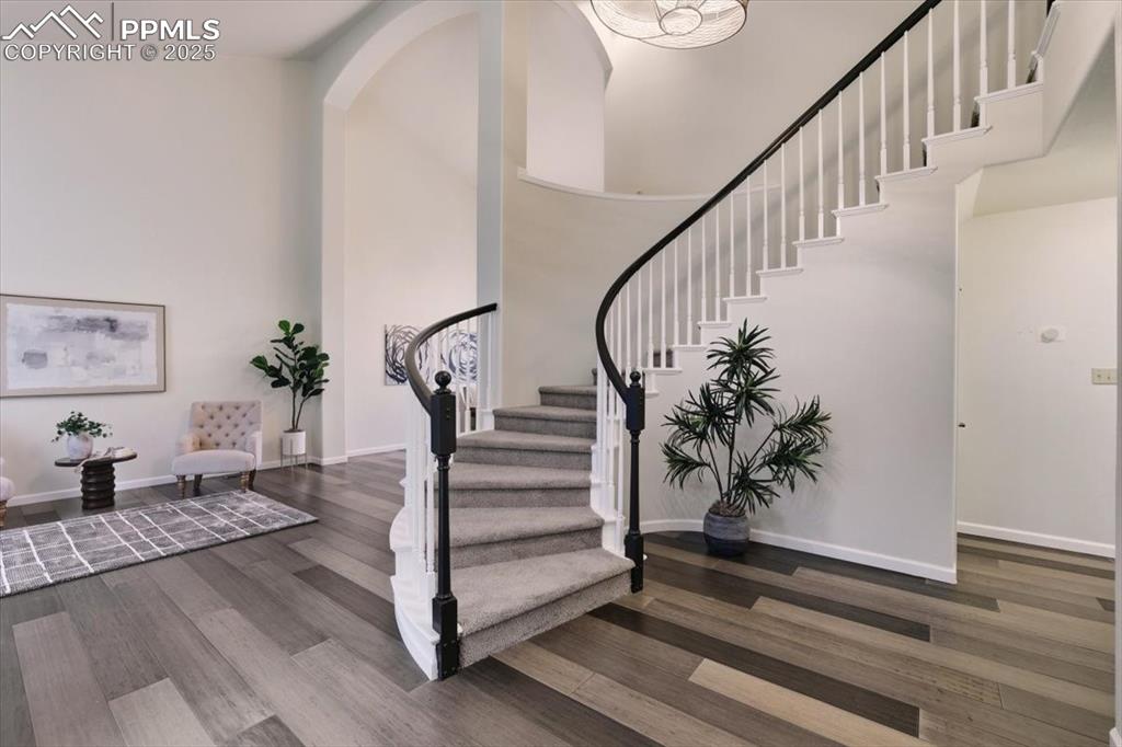 Image 2 of 31: Stairway featuring a high ceiling and wood finished floors