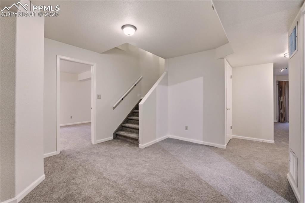 Image 24 of 31: Empty room with stairway and light colored carpet