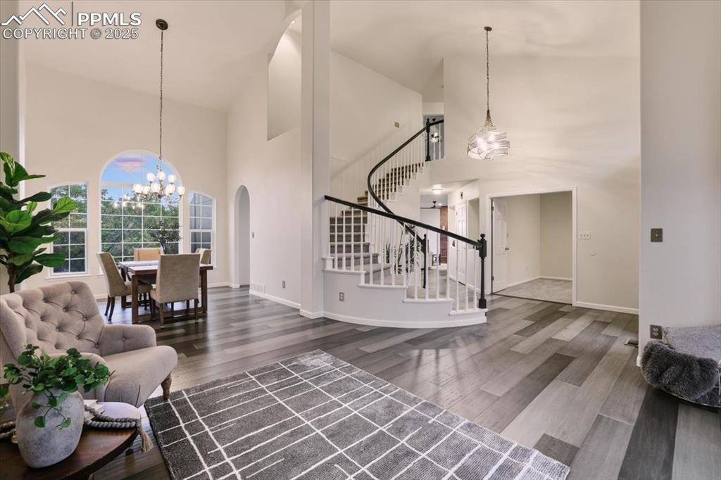 Image 3 of 31: Living room with high vaulted ceiling, a chandelier, dark wood-type floorin