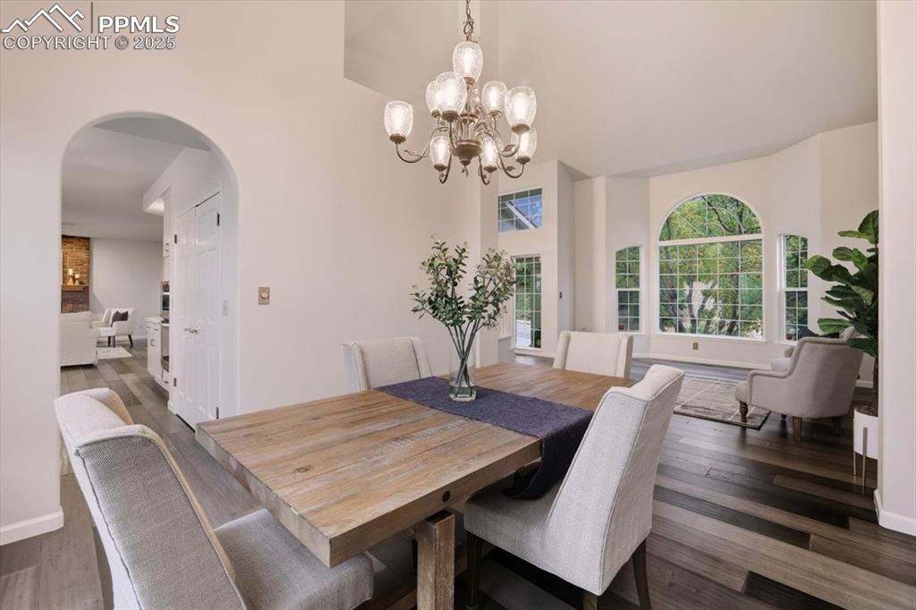 Image 4 of 31: Dining room featuring dark wood-style flooring, arched walkways, and a chan