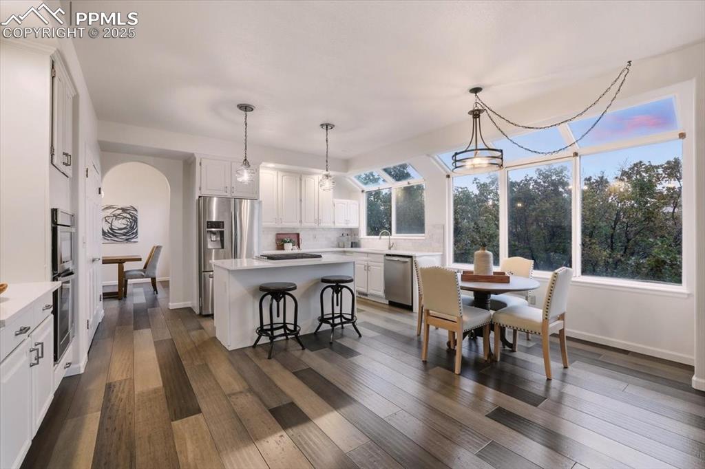 Image 5 of 31: Dining room with dark wood-style floors and arched walkways