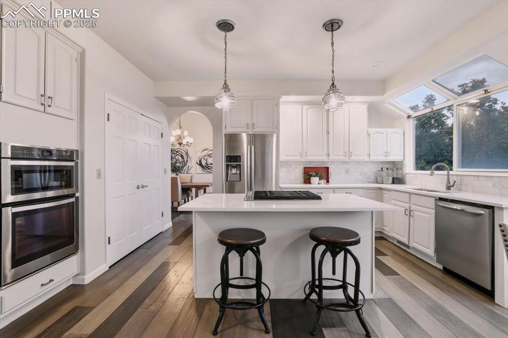 Image 6 of 31: Kitchen featuring a center island, white cabinets, backsplash, appliances w