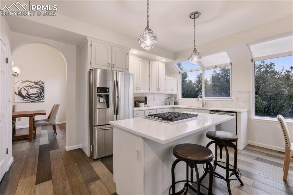 Image 7 of 31: Kitchen featuring stainless steel appliances, hanging light fixtures, white