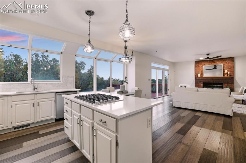 Image 9 of 31: Kitchen with white cabinets, decorative backsplash, hanging light fixtures,
