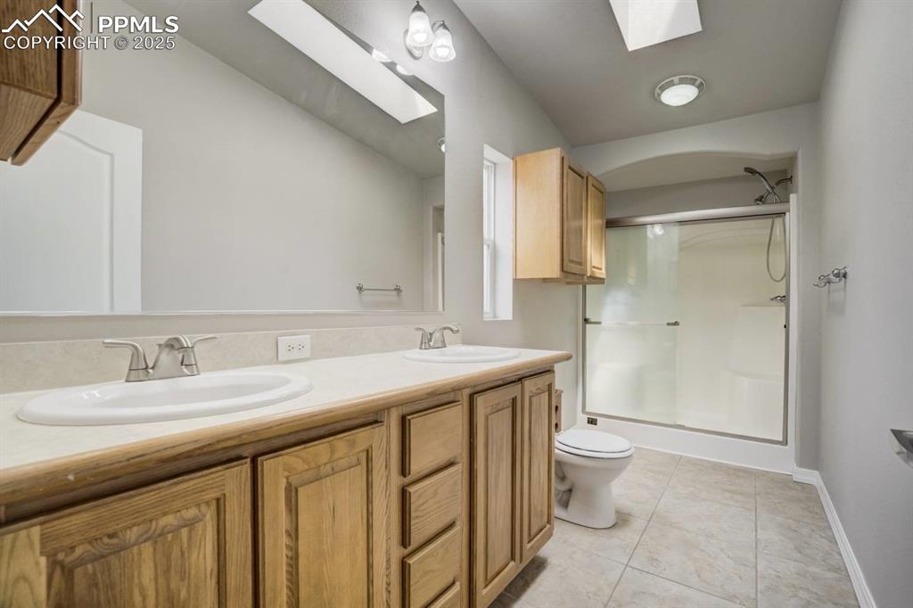 Image 14 of 35: Bathroom with a skylight, a stall shower, and light tile patterned floors