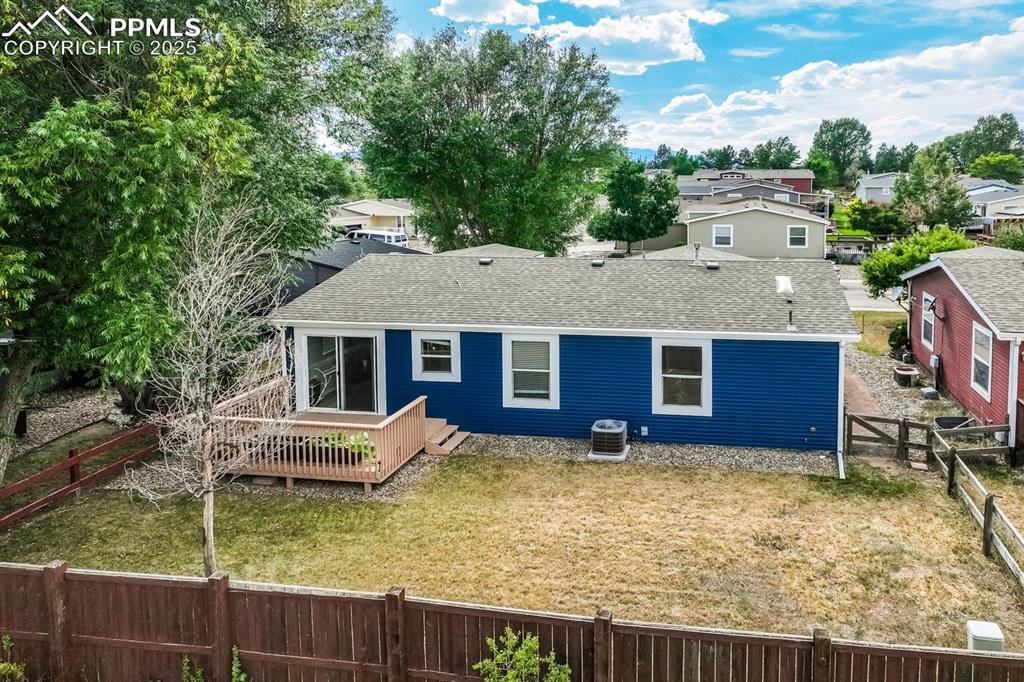 Image 27 of 35: Back of property featuring a shingled roof, a wooden deck, and a fenced bac