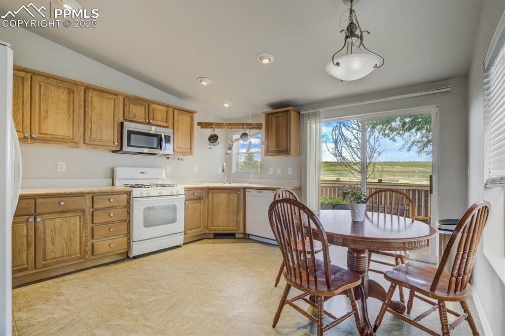 Image 6 of 35: Kitchen featuring pendant lighting, white appliances, lofted ceiling, light