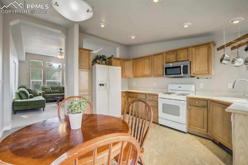 Image 9 of 35: Kitchen with white appliances, light countertops, recessed lighting, lofted