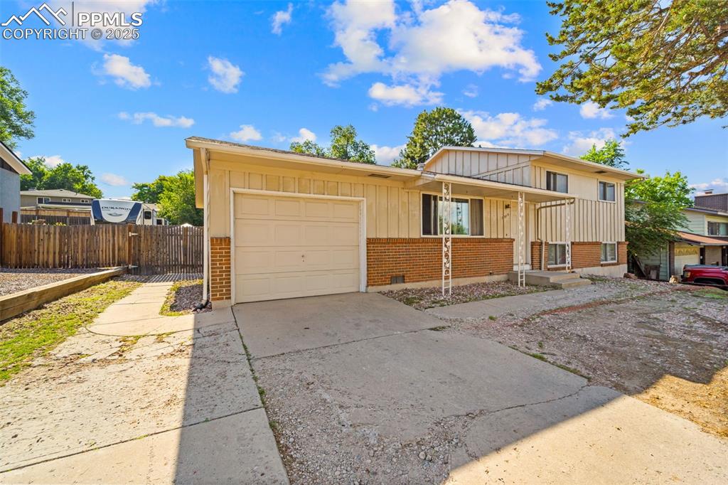 Image 10 of 38: View of front of house with brick siding, driveway, board and batten siding