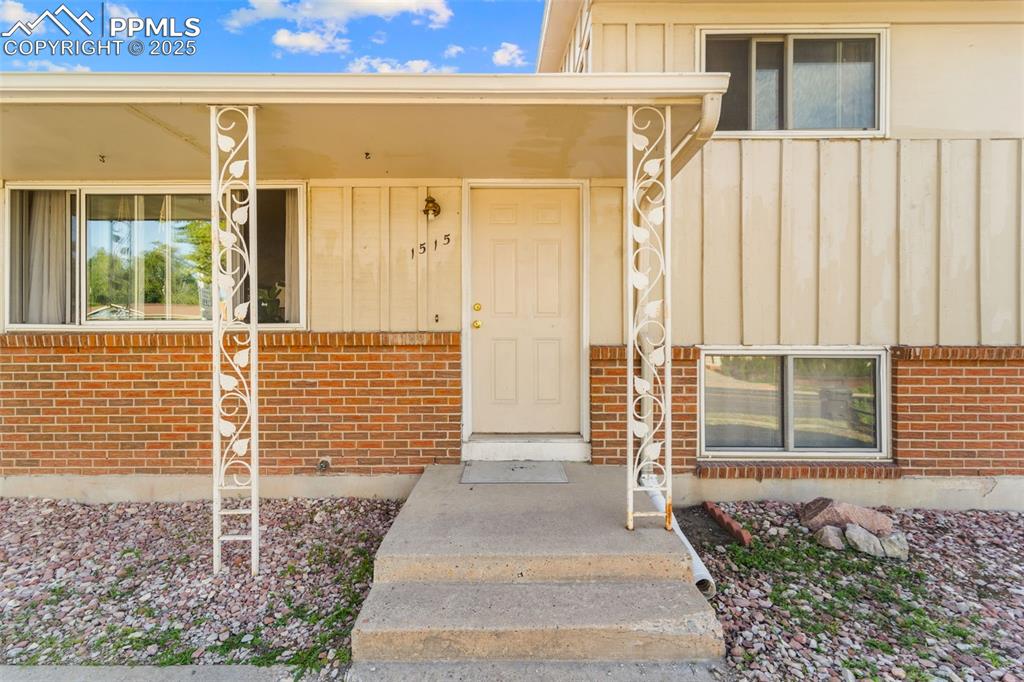 Image 11 of 38: Property entrance with board and batten siding and brick siding