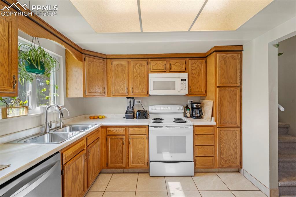 Image 19 of 38: Kitchen featuring white appliances, light tile patterned floors, light coun