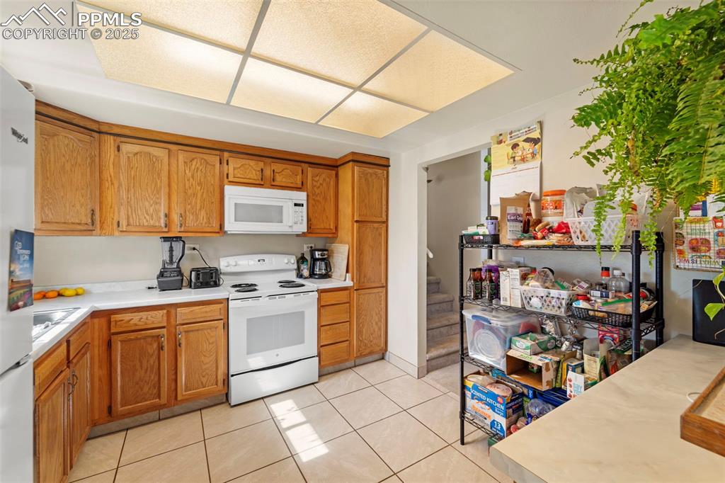 Image 22 of 38: Kitchen featuring white appliances, light countertops, light tile patterned