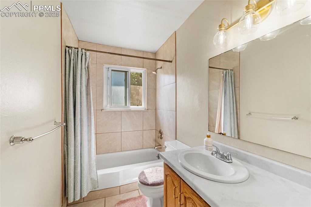 Image 23 of 38: Bathroom featuring vanity, shower / tub combo with curtain, and tile patter
