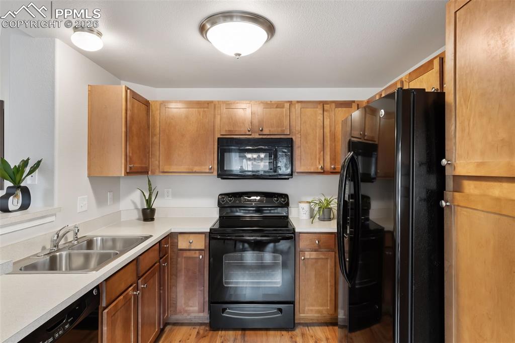 Image 10 of 26: Kitchen with black appliances, wood finish cabinetry, light countertops, an