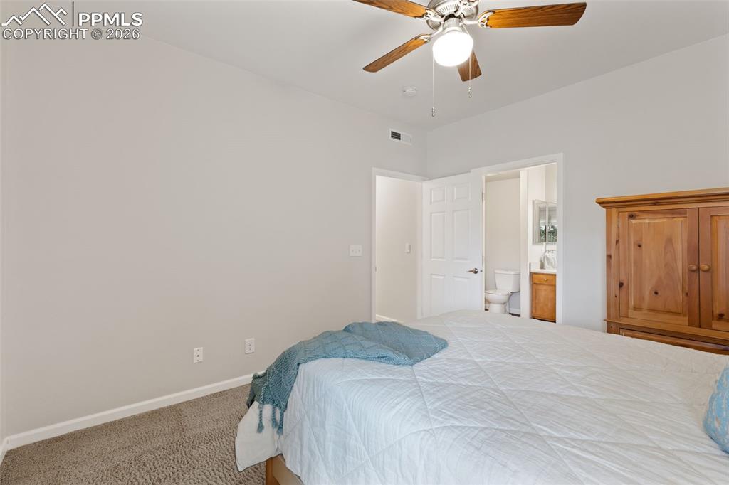 Image 15 of 26: Carpeted bedroom with a ceiling fan and ensuite bathroom