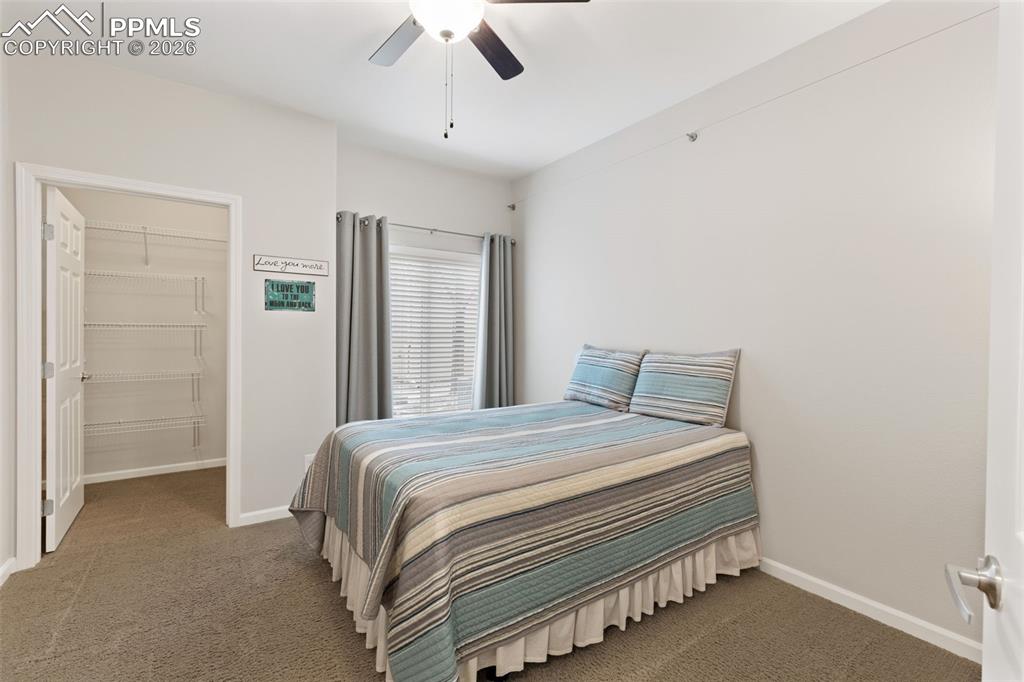 Image 19 of 26: Carpeted bedroom with a spacious closet and a ceiling fan