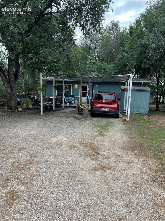 Caption: Gravel driveway leading to a covered entrance and carport